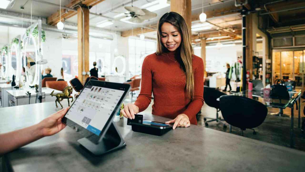Asian Female Shopper Swiping Credit Card at Salon